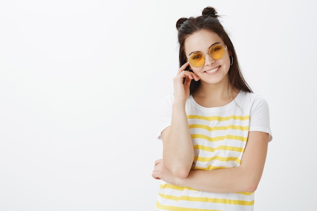 jeune femme, poser, à, lunettes soleil, contre, mur blanc