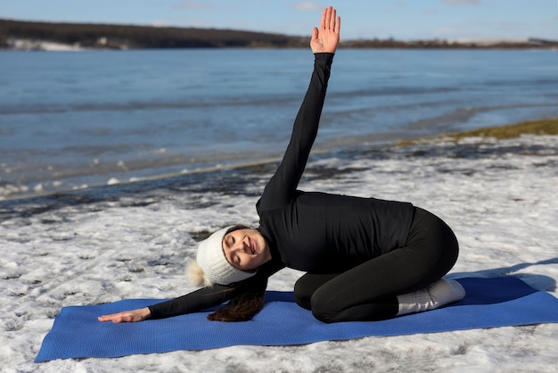 Jeune Femme Pratiquant Le Yoga à L'extérieur Pendant L'hiver Sur La Plage