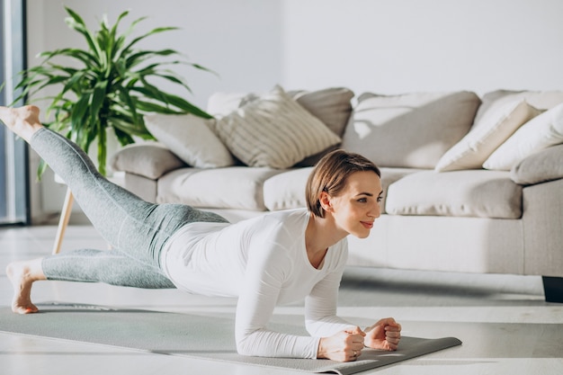 Jeune femme pratiquant le yoga à la maison sur le tapis