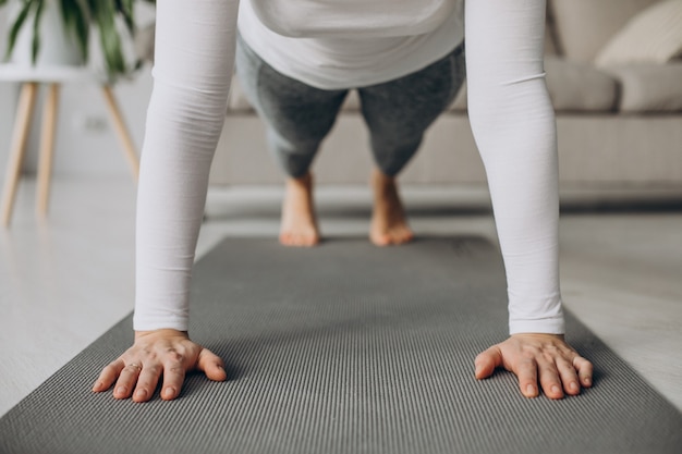 Jeune femme pratiquant le yoga à la maison sur le tapis