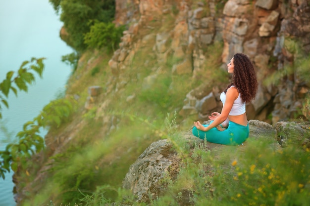 Jeune femme pratique le yoga près de la rivière