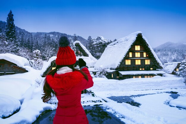 Jeune femme prenant une photo au village de Shirakawa-go en hiver, au Japon.