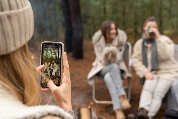 Jeune femme prenant une photo de ses amis buvant de l'eau à l'aide de son smartphone