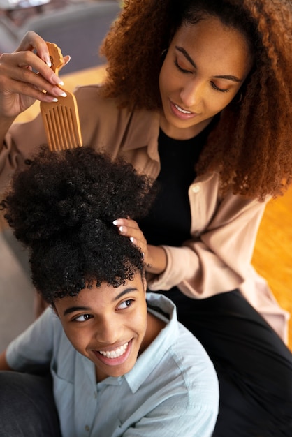 Jeune femme prenant soin des cheveux afro du garçon