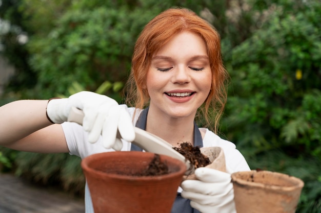 Photo gratuite jeune femme prenant soin de ses plantes dans une serre