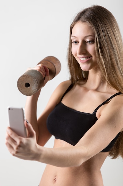 Jeune femme de prendre une photo tout en tenant un haltère