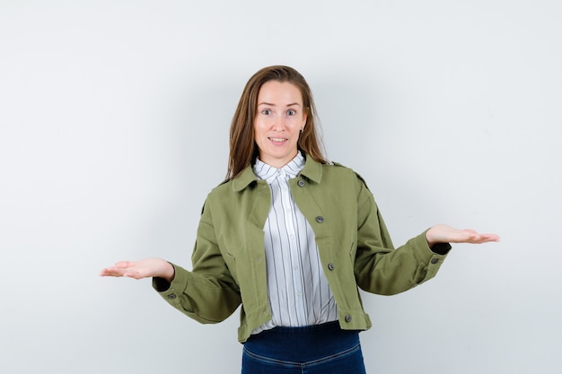 Photo gratuite jeune femme présentant ou comparant quelque chose en chemise, veste et semblant confiante. vue de face.