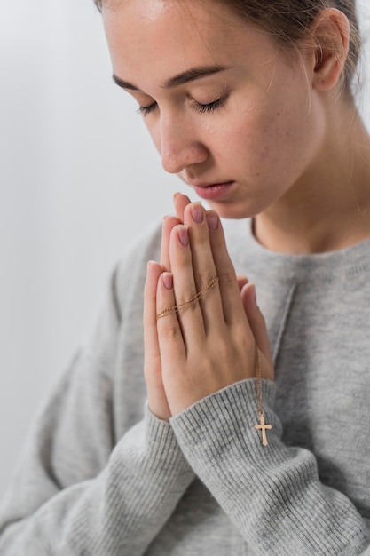 Photo gratuite jeune femme priant à la maison avec les yeux fermés