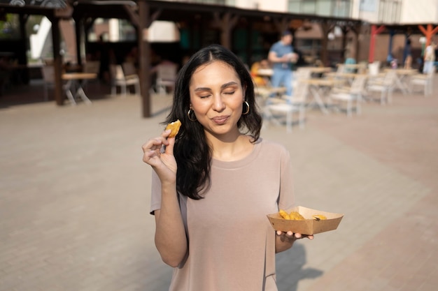 Photo gratuite jeune femme profitant de la nourriture de rue à l'extérieur
