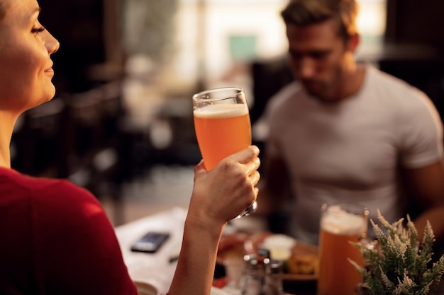 Photo gratuite jeune femme profitant d'un verre de bière tout en étant dans un pub avec son petit ami