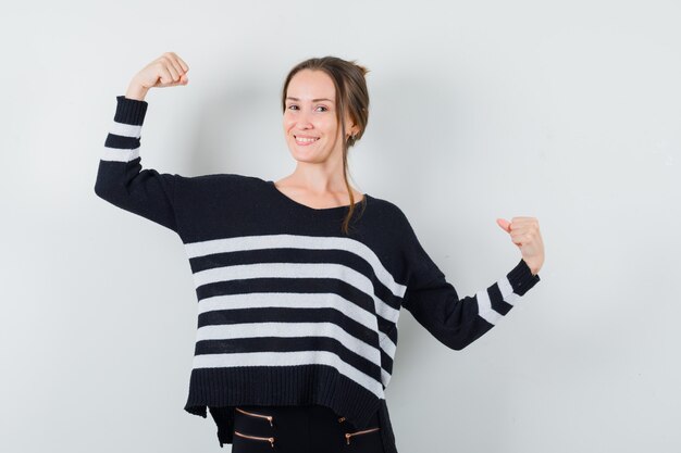 Jeune femme, projection, muscles, dans, maille rayée, et, pantalon noir, et, air heureux