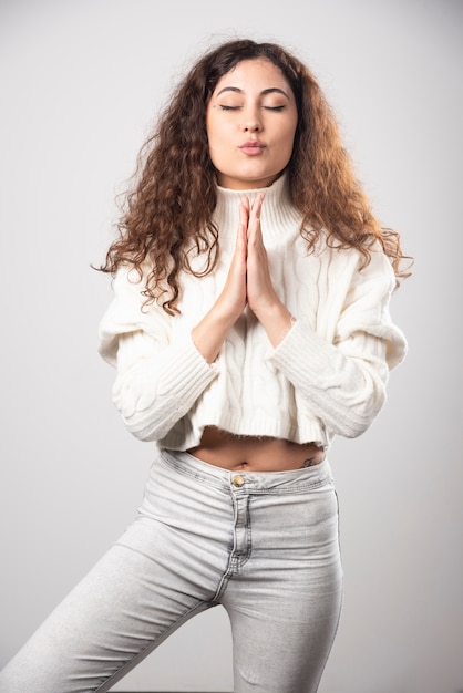 Jeune femme en pull blanc debout sur un mur blanc. Photo de haute qualité