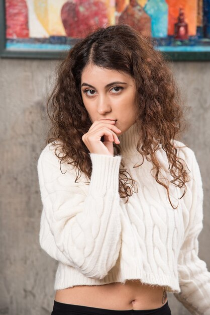 Jeune femme en pull blanc debout et posant