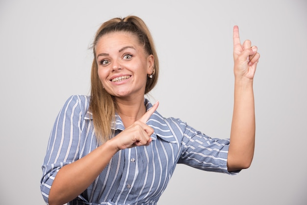 Jeune femme en pull bleu pointant sur quelque chose.