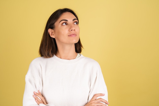 Jeune femme en pull chaud blanc réfléchie avec sourire