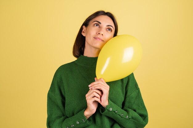 Jeune femme en pull chaud vert souriant avec ballon à air