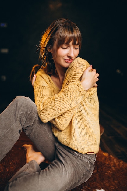 Jeune femme en pull jaune dans sa chambre