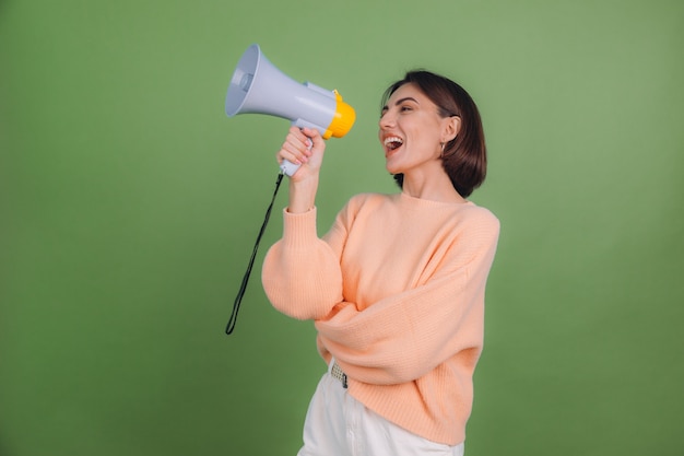 Jeune femme en pull pêche occasionnel isolé sur un mur de couleur olive verte