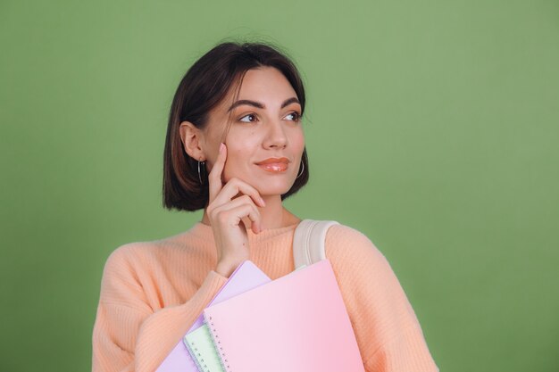 Jeune femme en pull pêche occasionnel isolé sur un mur de couleur olive verte