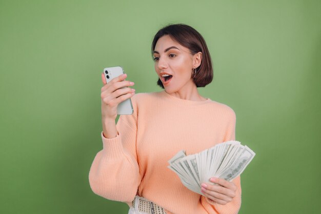 Jeune femme en pull pêche occasionnel isolé sur mur d'olive verte