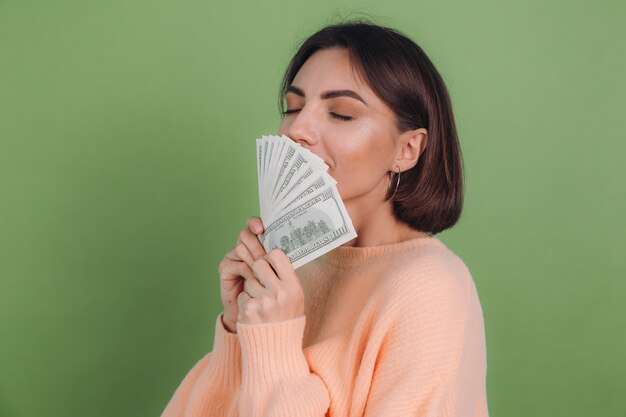 Jeune femme en pull pêche occasionnel isolé sur mur d'olive verte