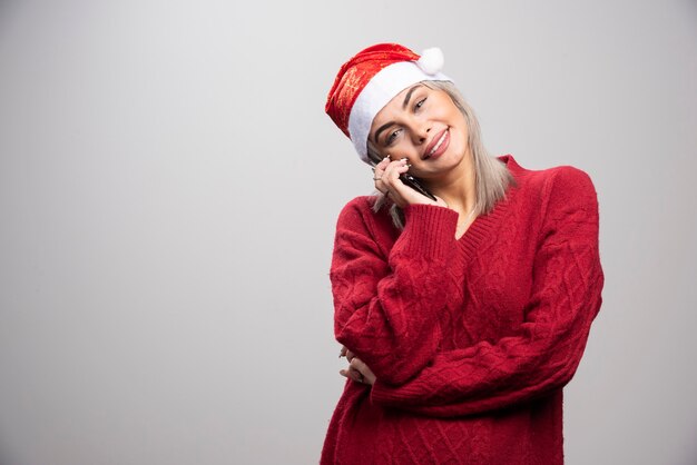 Jeune femme en pull rouge parlant au téléphone portable.