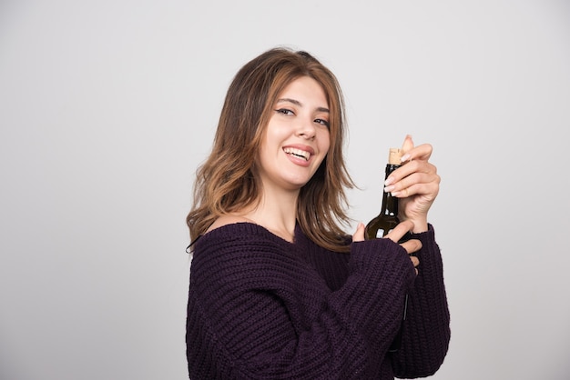Jeune femme en pull tricoté chaud tenant une bouteille de vin.