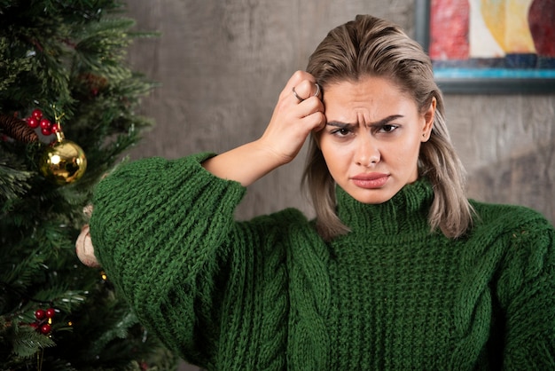 Jeune femme en pull vert touchant sa tête