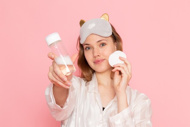 jeune femme en pyjama et masque de sommeil posant avec sourire sur rose