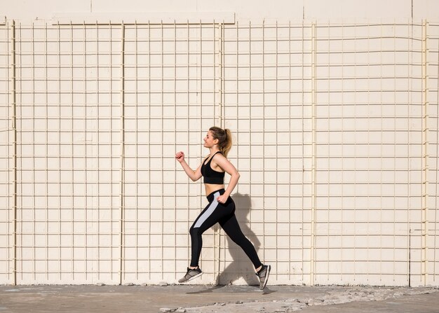 Jeune femme qui court à l&#39;extérieur avec des vêtements de sport