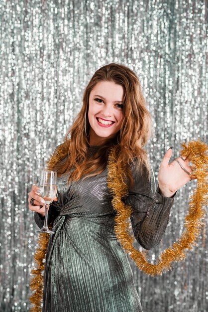 Jeune femme qui rit avec verre près de tinsel