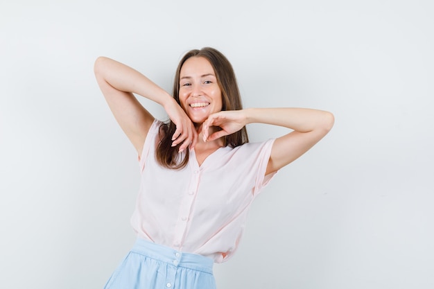 Jeune femme qui s'étend des coudes en t-shirt, jupe et à la joyeuse. vue de face.