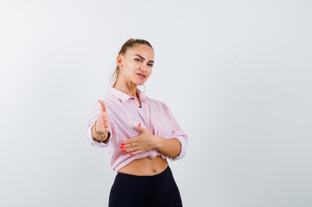 Jeune femme qui s'étend la main à la caméra en chemise décontractée et à la confiance. vue de face.