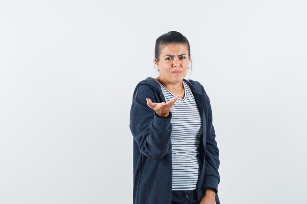 Jeune femme qui s'étend la main en geste perplexe en t-shirt