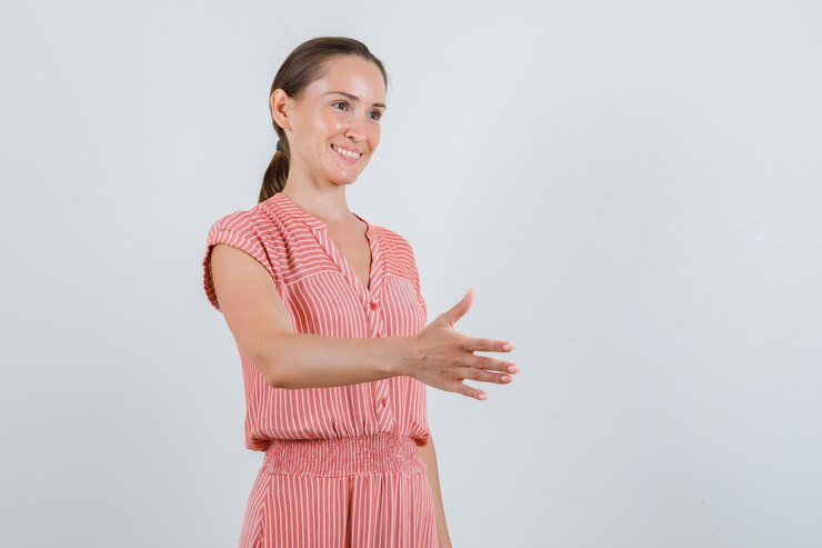 Photo gratuit jeune femme qui s'étend de la main pour secouer en robe rayée et à la joyeuse vue de face.