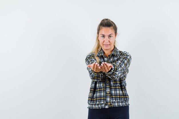 Photo gratuite jeune femme qui s'étend les mains en coupe en chemise, short et élégant, vue de face.