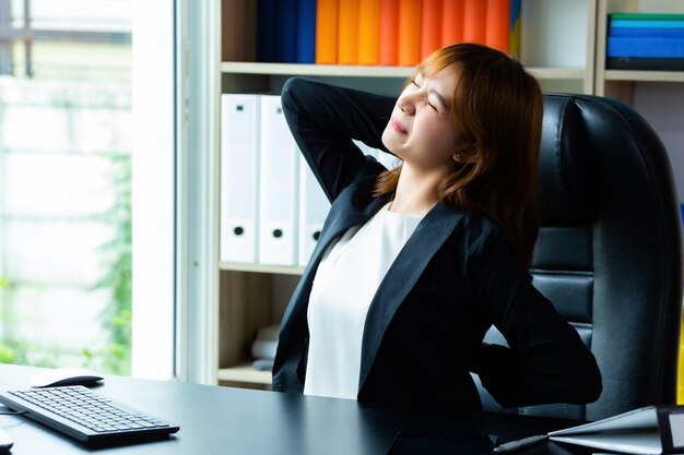 Jeune femme qui travaille a mal au dos au bureau