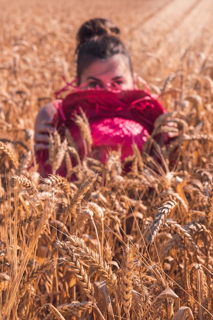 Jeune femme de race blanche dans une belle robe rouge profitant du temps ensoleillé dans un champ de blé