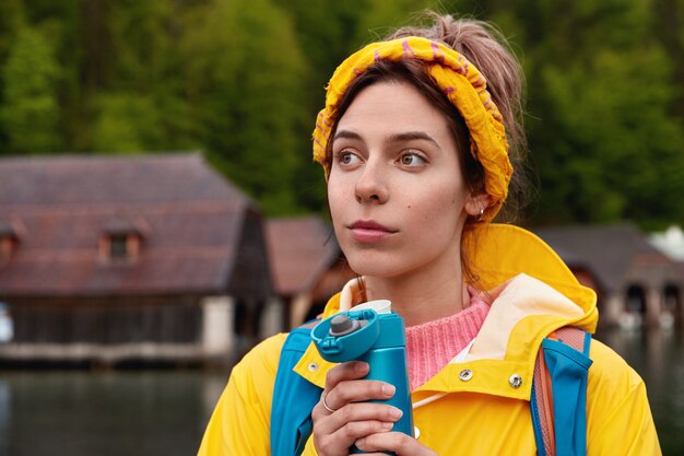 Jeune femme de race blanche réfléchie porte une écharpe jaune et un anorak