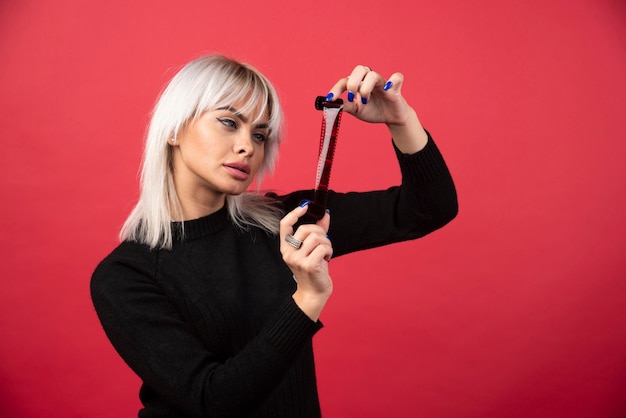 Jeune femme à la recherche d'une cassette photo sur fond rouge. Photo de haute qualité