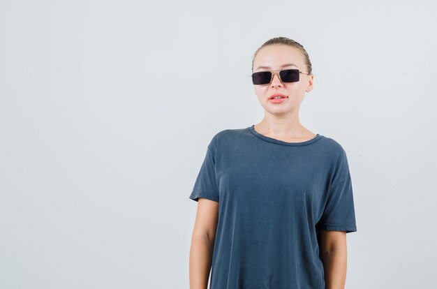 Jeune femme à la recherche de t-shirt gris, lunettes et à la jolie