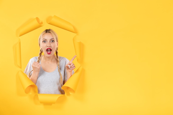 Photo gratuit jeune femme à la recherche de la vente d'intérieur de fenêtre faciale de fond de papier jaune déchiré