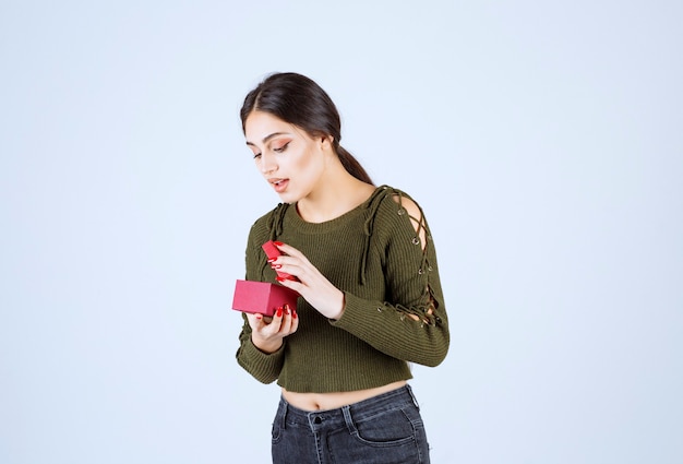 Jeune femme regardant boîte-cadeau sur fond blanc.