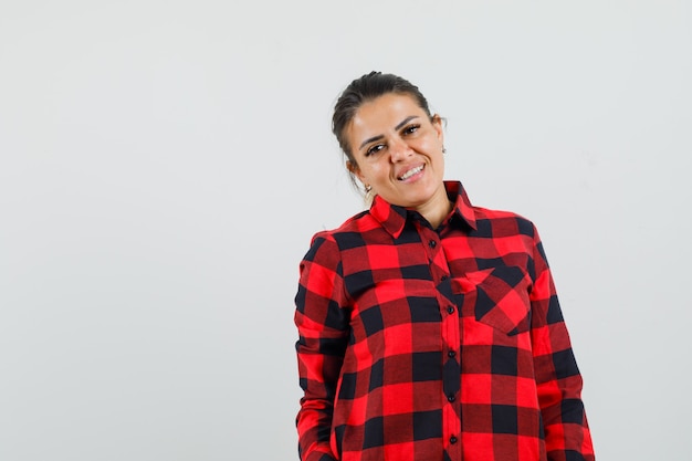 Jeune femme regardant la caméra en chemise à carreaux et à la joyeuse