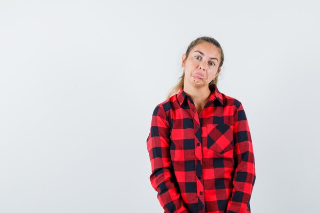 Jeune femme regardant la caméra en chemise décontractée et à la perplexe. vue de face.