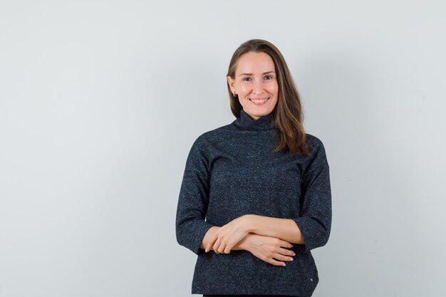 Jeune femme regardant la caméra en chemise et à la recherche de bonne humeur. vue de face.