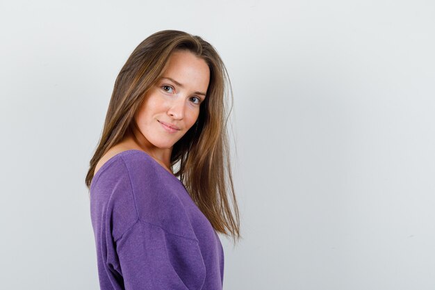 Jeune femme regardant la caméra en chemise violette et à la belle.