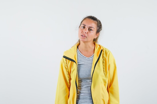 Jeune Femme Regardant La Caméra En T-shirt, Veste Et à La Perplexité. Vue De Face.