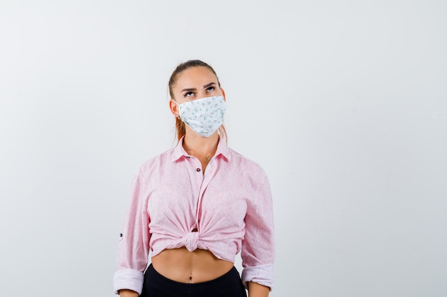 Jeune femme regardant en chemise, masque et à la pensif. vue de face.