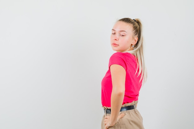 Jeune femme regardant par-dessus son épaule en t-shirt et pantalon et à la tentation